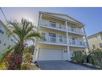 Three-story beach house featuring double balconies, complemented by vibrant pink flowers at 703 37Th Ave. S, North Myrtle Beach, SC 29582