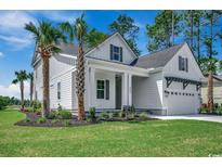 Beautiful two-story home with a well-manicured lawn, lovely landscaping, and an attached garage at 1142 Fiddlehead Way, Myrtle Beach, SC 29579