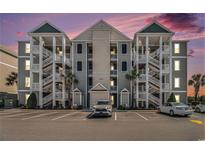 Attractive condo building with multiple floors, exterior staircases, and ample parking at dusk at 189 Ella Kinley Circle # 201, Myrtle Beach, SC 29588