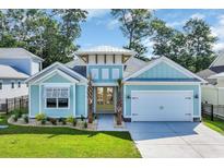 Charming, light blue single story home with a two car garage, lovely landscaping, and a sunny yellow front door at 1940 Indigo Cove Ln, Calabash, NC 28467