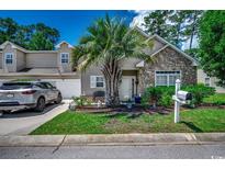 Charming home with stone accents, a landscaped yard, and a welcoming entrance with a palm tree at 4294 Rivergate Ln., Little River, SC 29566