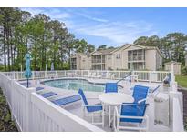 Inviting community pool area with lounge chairs and tables, surrounded by lush greenery and well-maintained buildings at 4507 Sweetwater Blvd. # 4507, Murrells Inlet, SC 29576
