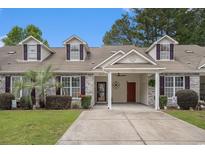 Charming townhome featuring a covered carport, brick accents, manicured lawn, and dormer windows at 511 Colonial Trace Dr. # 7-C, Longs, SC 29568