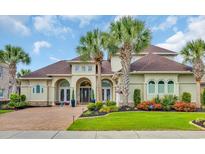 Stunning home with a well-manicured lawn, lush flowerbeds, brick driveway, and beautiful palm trees at 603 Sea Island Way, North Myrtle Beach, SC 29582