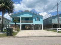 Charming stilted coastal home with a light blue exterior, wood railings, and well-manicured landscaping at 6205 Nixon St., North Myrtle Beach, SC 29582