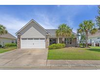 Charming single-story home with a well-manicured lawn and attached two-car garage at 691 Sandberg St., Surfside Beach, SC 29575
