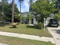 Charming one-story home with a well-manicured lawn, mature trees, and a driveway at 105 E Retreat Pl., Little River, SC 29566