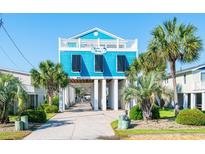 Beautiful raised beach house with blue siding, white pillars, a front deck, and lush palm trees at 163 Cypress Ave., Murrells Inlet, SC 29576