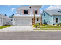 Charming two-story home featuring a light-colored exterior, lush landscaping and a two car garage at 1957 Indigo Cove Ln, Calabash, NC 28467