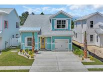 Charming light-blue two-story home with a welcoming yellow door and well-maintained landscaping at 1961 Indigo Cove Ln, Calabash, NC 28467