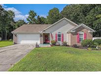 Charming single-story home featuring a well-manicured lawn, brick accents, red shutters, and an attached garage at 271 Sienna Dr., Little River, SC 29566