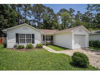 Charming single-story home with a well-manicured lawn, white siding, and attached garage in a lush, green neighborhood at 2768 Temperance Dr., Myrtle Beach, SC 29577