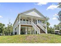 Charming stilt home featuring a spacious porch, well-manicured lawn, and inviting staircase at 400 Elizabeth Dr., Murrells Inlet, SC 29576