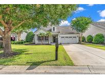 Charming single-story home featuring a well-manicured lawn, inviting porch, and attached two-car garage at 4548 Marshwood Dr., Myrtle Beach, SC 29579