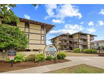 Exterior shot of Heron Pond buildings with a blue sky and the complex sign with landscaping at 6813 Porcher Dr. # 21, Myrtle Beach, SC 29572