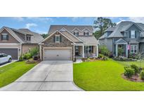 Charming two-story home featuring a manicured lawn and a welcoming front porch with seating at 7317 Lieth Ln., Sunset Beach, NC 28468