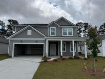 New two-story home featuring a covered entryway, gray siding, attached two-car garage and a green lawn at 1023 Laconic Dr., Myrtle Beach, SC 29588