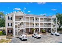 Three-story building with brick accents, stairs and white railings, and parking with several cars at 1058 Sea Mountain Hwy. # 9-101, North Myrtle Beach, SC 29582
