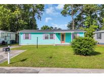 Charming home featuring a well-manicured lawn, teal siding and purple shutters, creating a welcoming curb appeal at 1107 Blue Ridge Trail, North Myrtle Beach, SC 29582