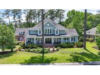 Charming light blue two-story home with a welcoming front porch, lush landscaping, and mature trees at 160 Stonington Dr., Murrells Inlet, SC 29576