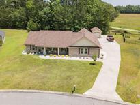 Charming brick home boasts a well-manicured lawn, inviting front porch, and long driveway leading to a detached garage at 193 Field Loop Rd., Georgetown, SC 29440
