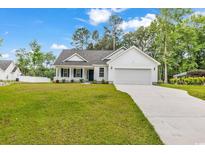 Charming single-story home with a well-manicured lawn and long driveway leading to an attached garage at 255 Yauhanna Lake Dr., Georgetown, SC 29440