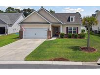 Charming single-story home featuring well-manicured lawn, two-car garage, and mature palm tree at 309 Rycola Circle, Surfside Beach, SC 29575