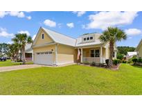 Charming yellow home featuring a metal roof, a welcoming front porch, and a well-manicured lawn at 323 Waties Dr., Murrells Inlet, SC 29576