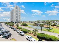 A high-rise condo building overlooks a parking lot, a pond with a fountain, palm trees, and the ocean in the distance at 5905 South Kings Hwy., Myrtle Beach, SC 29575