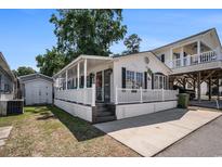 Charming white home featuring a welcoming porch and well-maintained landscaping at 6001-1833 S Kings Hwy., Myrtle Beach, SC 29575