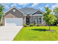 Charming brick home with a well-manicured lawn and two-car garage on a sunny day at 644 Harbor Bay Dr., Murrells Inlet, SC 29576