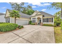 Charming single-story home with a two-car garage, neutral siding and a well-manicured yard and driveway at 67 Camden Circle, Pawleys Island, SC 29585