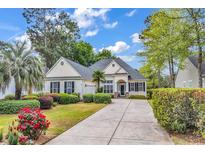 Charming single story home with driveway, manicured lawn, and colorful flower beds at 67 Camden Circle, Pawleys Island, SC 29585