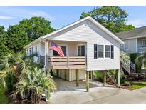 Charming coastal home on stilts with a cozy porch and American flag at 9679 Stillwater Ct., Myrtle Beach, SC 29572