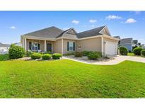 Charming tan home featuring a well-manicured lawn and landscaped garden beds at 388 Hillsborough Dr., Conway, SC 29526
