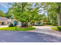 Charming home features manicured lawn and a circular driveway, surrounded by mature trees at 444 Dornoch Dr., Pawleys Island, SC 29585