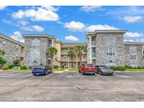 Beautiful multi-story condo building with stone accents and manicured landscaping, located next to parking area at 4705 Wild Iris Dr. # 305, Myrtle Beach, SC 29577