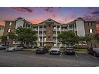 Beautiful condo building with multiple balconies, brick accents, and well-manicured landscaping at dusk at 4895 Luster Leaf Circle # 302, Myrtle Beach, SC 29577