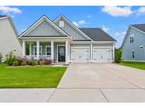 Charming home with a two-car garage, covered porch, manicured lawn, and gray board and batten siding at 5605 Whitebark Dr., Myrtle Beach, SC 29577