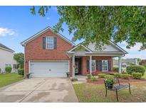 Charming brick home with a two-car garage, landscaped yard, and cozy front porch seating at 600 Tattlesbury Dr., Conway, SC 29526