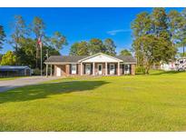 Charming one-story brick home with a lush green lawn and a welcoming front porch with rocking chairs at 64 Highway 521, Andrews, SC 29510
