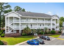 Exterior of multi-story condominium featuring white balconies, brick accents, and well-maintained landscaping at 682 Riverwalk Dr. # 102, Myrtle Beach, SC 29579