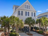 Charming stilted home with palm trees offers coastal living at its finest with dark blue shutters and beach views at 703 S Waccamaw Dr., Garden City Beach, SC 29576