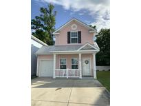 Charming pink two-story home with a front porch, white railings, and a well-maintained lawn at 739 Shell Creek Circle # 739, North Myrtle Beach, SC 29582