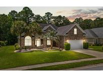 Charming brick home with a well-manicured lawn and mature palm trees at sunset at 950 Henry James Dr., Myrtle Beach, SC 29579