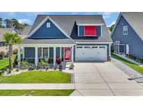 Charming blue home featuring a two-car garage, front lawn, tasteful landscaping, and a covered front porch at 1012 Mary Read Dr., North Myrtle Beach, SC 29582