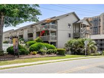Exterior view of a condo with multiple balconies, showcasing lush landscaping and mature trees at 202 Maison Dr. # L-301, Myrtle Beach, SC 29572