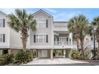 Desirable raised beach home featuring neutral siding, open carport, and lush landscaping with mature palms at 212 Millwood Dr., Surfside Beach, SC 29575