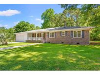 Charming brick home featuring a well-manicured lawn and a quaint front porch with a lovely sunburst design at 2415 Magnolia Lane, Little River, SC 29566