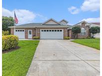 Well-maintained brick home featuring a three-car garage, a lush green lawn, and a welcoming entrance at 2479 Glen Dr., Little River, SC 29566